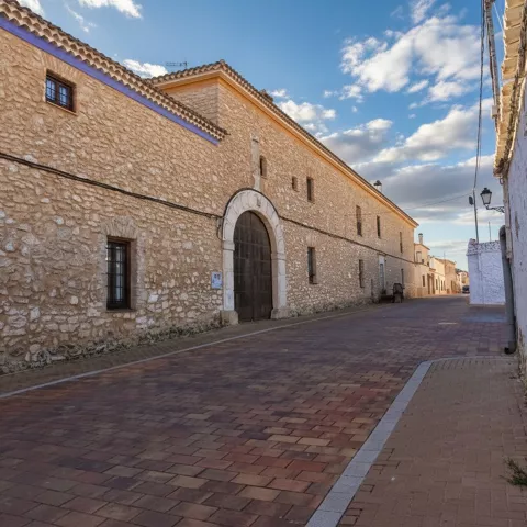 Calle de Minaya con edificio histórico de fachada de piedra y gran portada de arco.