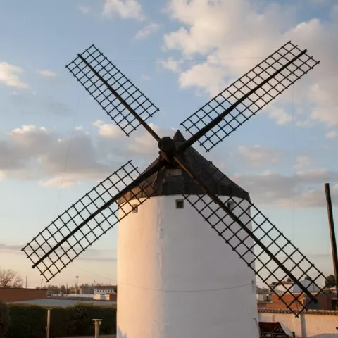 Molino tradicional iluminado al atardecer con cielo parcialmente nublado.
