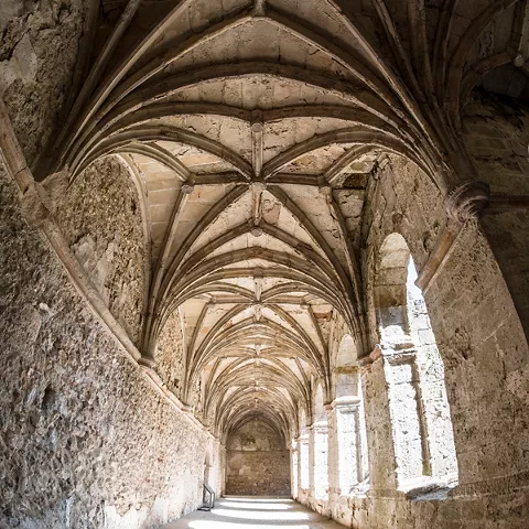 Pasillo con bóvedas góticas y luz lateral.