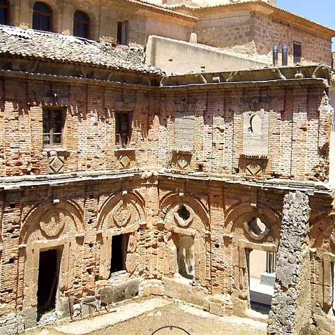 Claustro de ladrillo con arcos decorados.