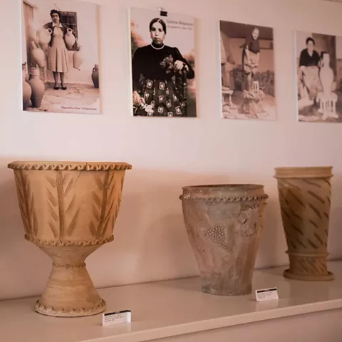 Exposición de vasijas de barro con fotografías antiguas en la pared.
