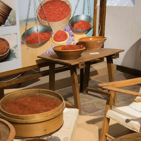 Recipientes y balanzas con hebras rojas en exposición etnográfica.