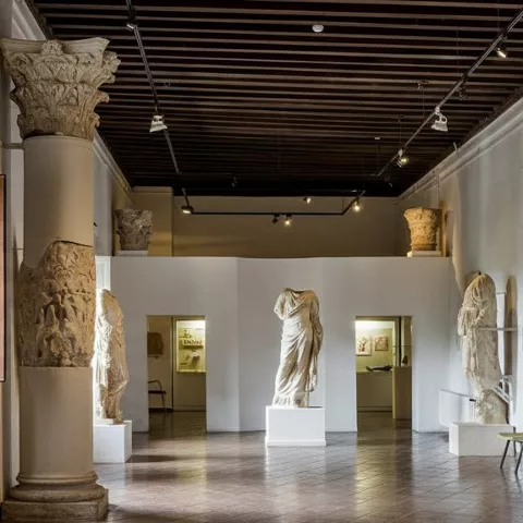 Galería luminosa con columnas y estatua central.