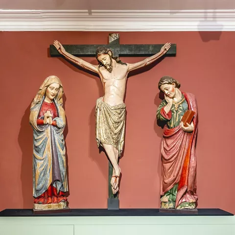 Conjunto escultórico con crucificado y figuras laterales.