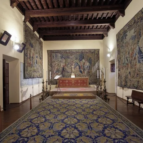 Sala con tapices antiguos y altar decorado.