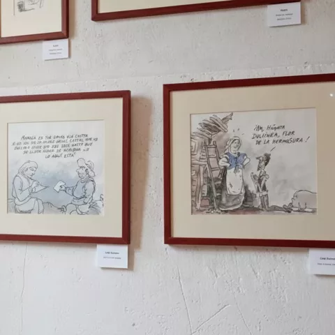 Detalle de ilustraciones enmarcadas con escenas humorísticas en pared blanca.