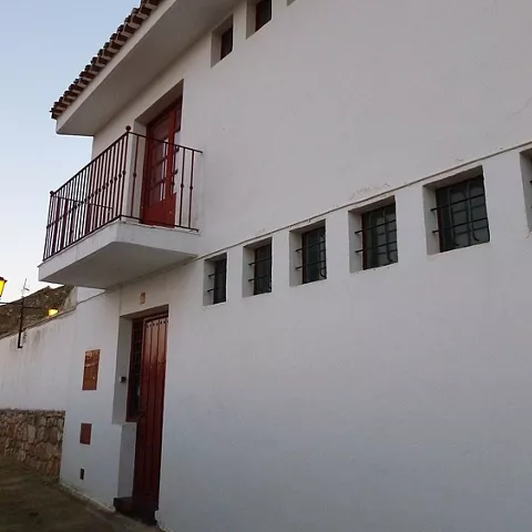 Fachada blanca de edificio tradicional con balcón pequeño y ventanas rectangulares.