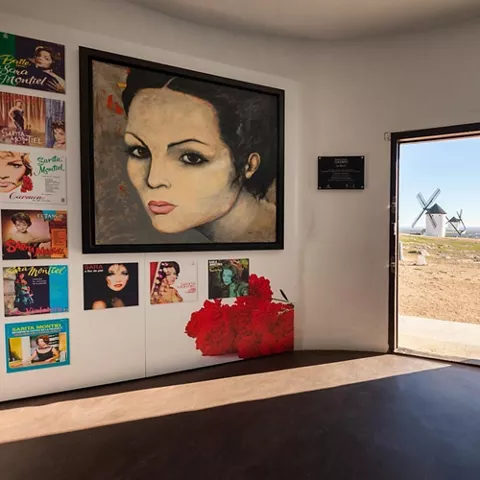 Espacio expositivo con gran retrato y puerta abierta al paisaje
