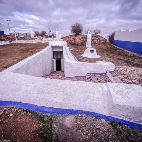 Entrada subterránea encalada en paisaje abierto