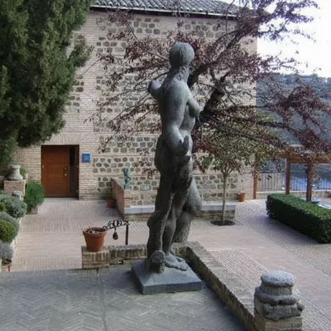 Patio con estatua central y edificio de fachada rústica.