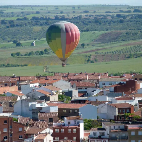 Globo aerostático sobre tejados y campos verdes