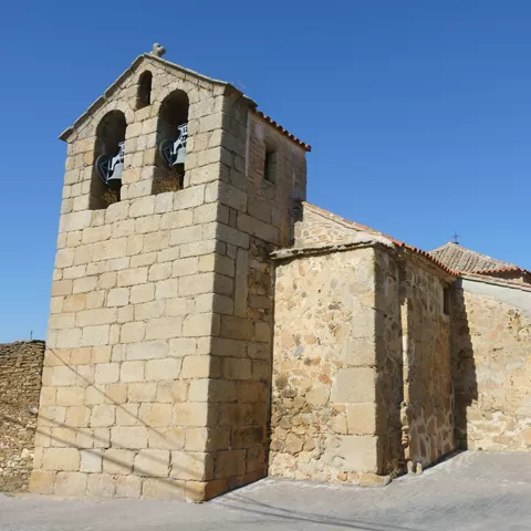 Campanario de piedra junto a iglesia bajo cielo despejado