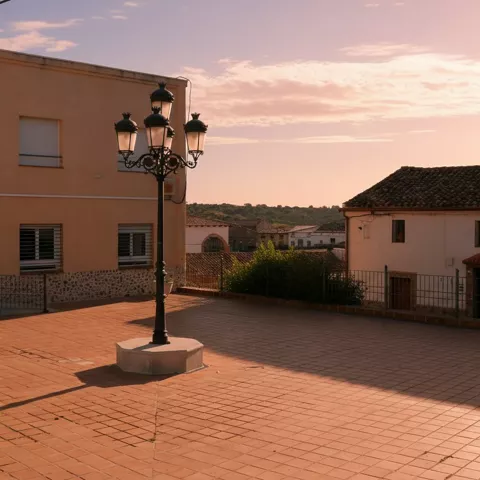 Plaza del Ayuntamiento de Navalpino (Ciudad Real) al atardecer, con farola central y edificios municipales.