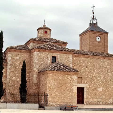 Iglesia de piedra con torre del reloj y cipreses