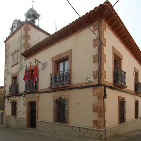 Fachada de ayuntamiento en esquina con torre del reloj y balcones
