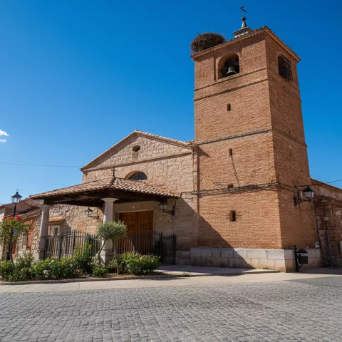 Iglesia de ladrillo y piedra con torre campanario y nido en lo alto