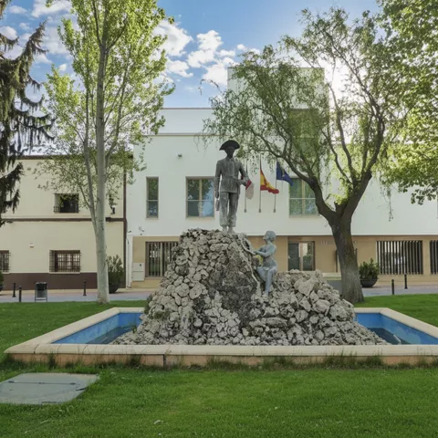 Monumento escultórico en jardín frente a edificio municipal