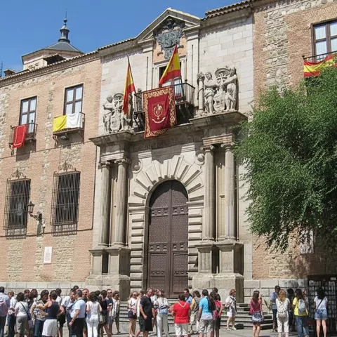 Grupo de personas frente a edificio histórico con gran portada central.