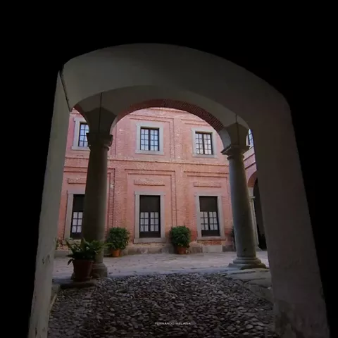 Patio interior de ladrillo visto enmarcado por un arco