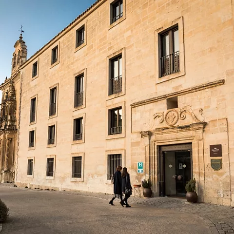 Entrada de edificio histórico en plaza empedrada.