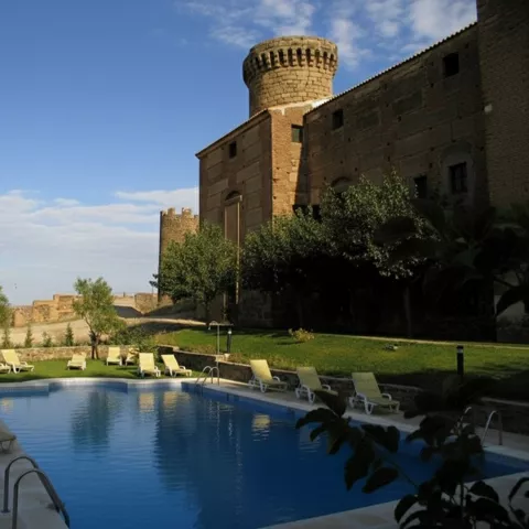 Piscina exterior junto a edificio de piedra con torre circular.