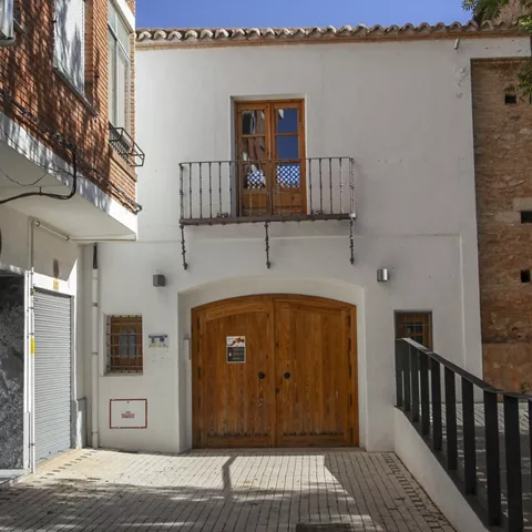 Fachada blanca con balcón y puerta de madera