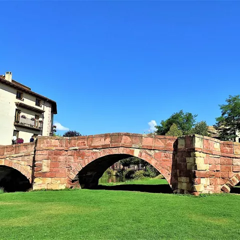 Arcos de piedra sobre pradera junto al agua.