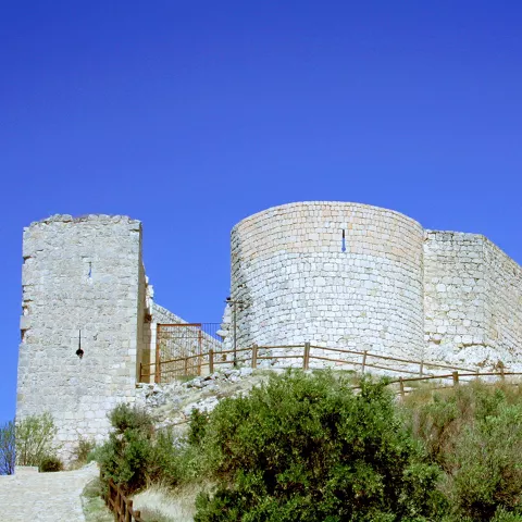 Torre circular y muros defensivos de piedra clara.