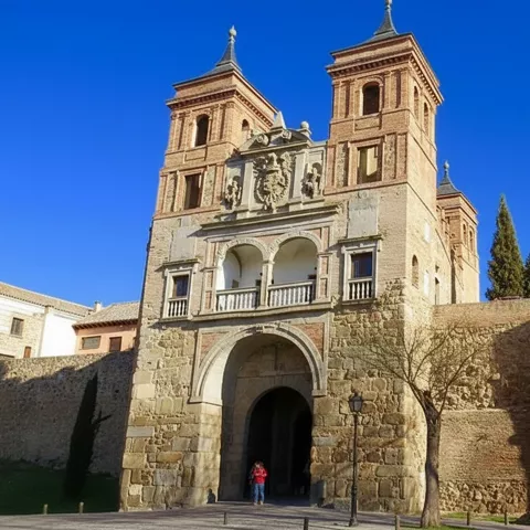 Puerta monumental de ladrillo y piedra con torres gemelas sobre muralla.