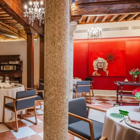 Salón con vigas de madera, columnas y mesas preparadas para servicio.