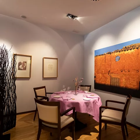 Mesa redonda con mantel rosa y cuadro mural