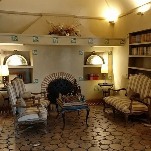 Sala de estar con chimenea, sofás clásicos y mesa central.