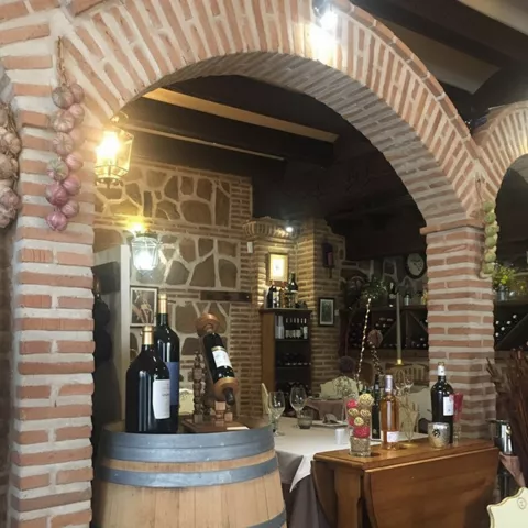 Interior acogedor con barrica decorativa, botellas de vino y mobiliario clásico.