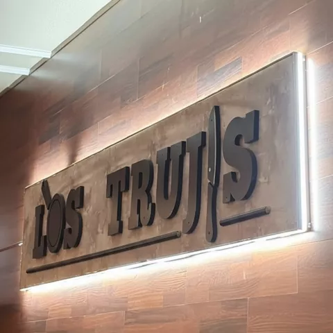 Rótulo metálico sobre pared de madera en el interior del local.