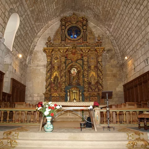 Interior de iglesia con retablo histórico.