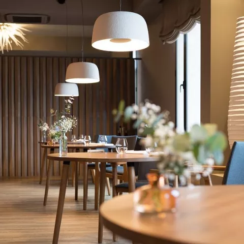 Comedor elegante con mesas redondas y lámparas colgantes