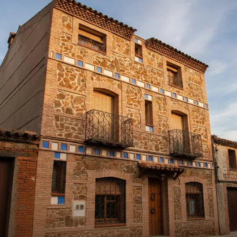 etalle de la fachada de una casa de campo singular, construida con piedra irregular y decorada con hileras horizontales de azulejos azules y blancos.