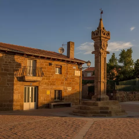 Columna monumental de piedra junto a una casa al atardecer