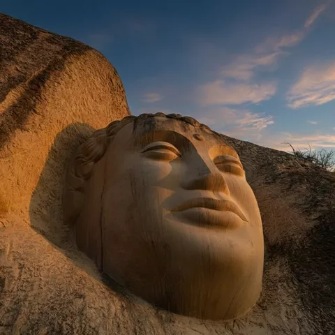 Rostro gigante tallado en roca al atardecer