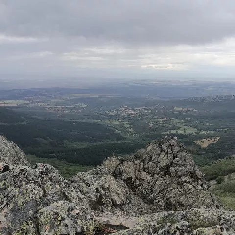 Panorámica de valle y montañas rocosas bajo cielo gris.