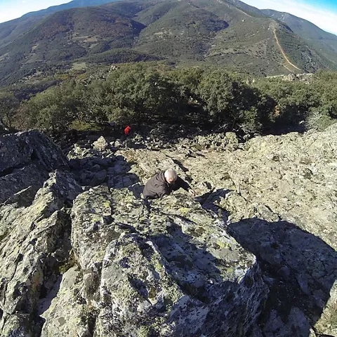 Excursionista escalando entre rocas con monte al fondo