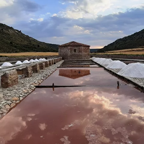 Montones de sal blanca junto a balsas al atardecer.