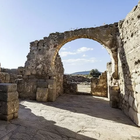 Ruinas de piedra con arco abierto bajo cielo despejado.