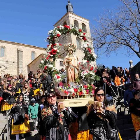 Procesión con figura adornada y participantes con trajes tradicionales.