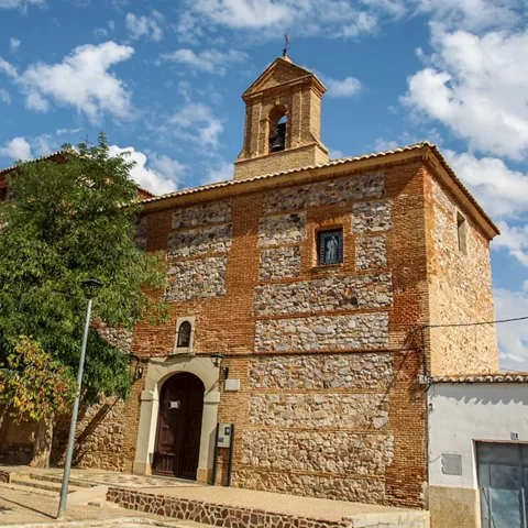 Iglesia de piedra con espadaña y árbol