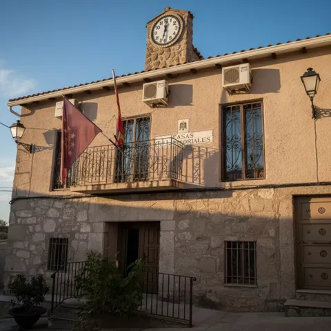 Casa consistorial de piedra con balcón y reloj