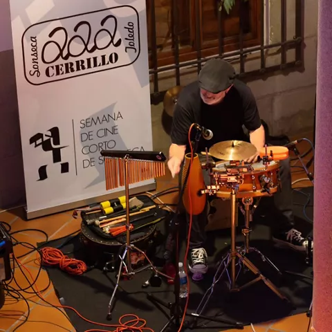 Percusionista actuando junto a cartel de festival