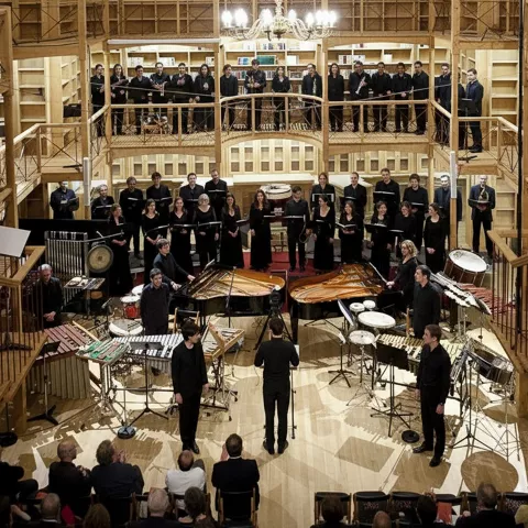 Conjunto vocal e instrumental en auditorio de madera