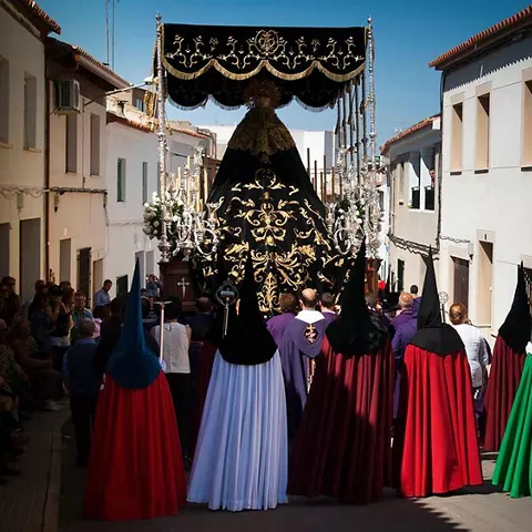 Paso procesional con palio avanzando por una calle estrecha