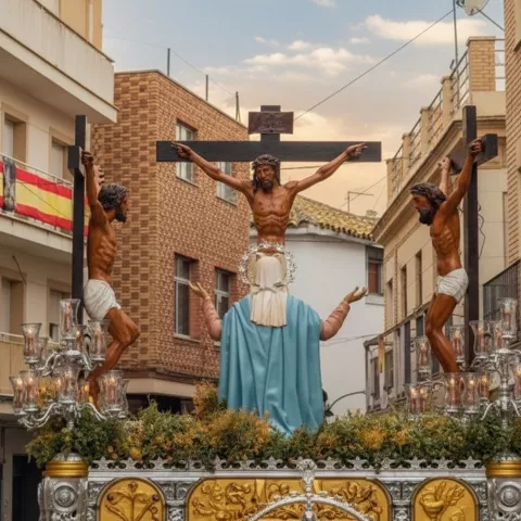 Paso con crucifixión y figura central en calle urbana.